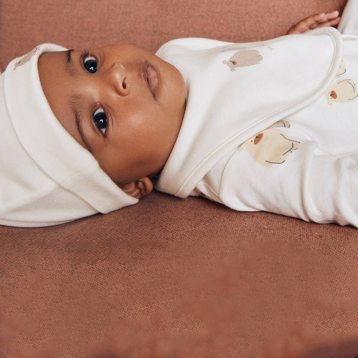 תינוק לובש תלבושת תואמת בצבע קרם. בגדי תינוקות